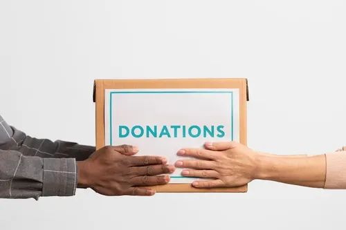 Two hands passing a donations box