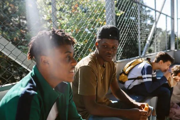 A group of young adults sitting together outdoors, talking and smiling