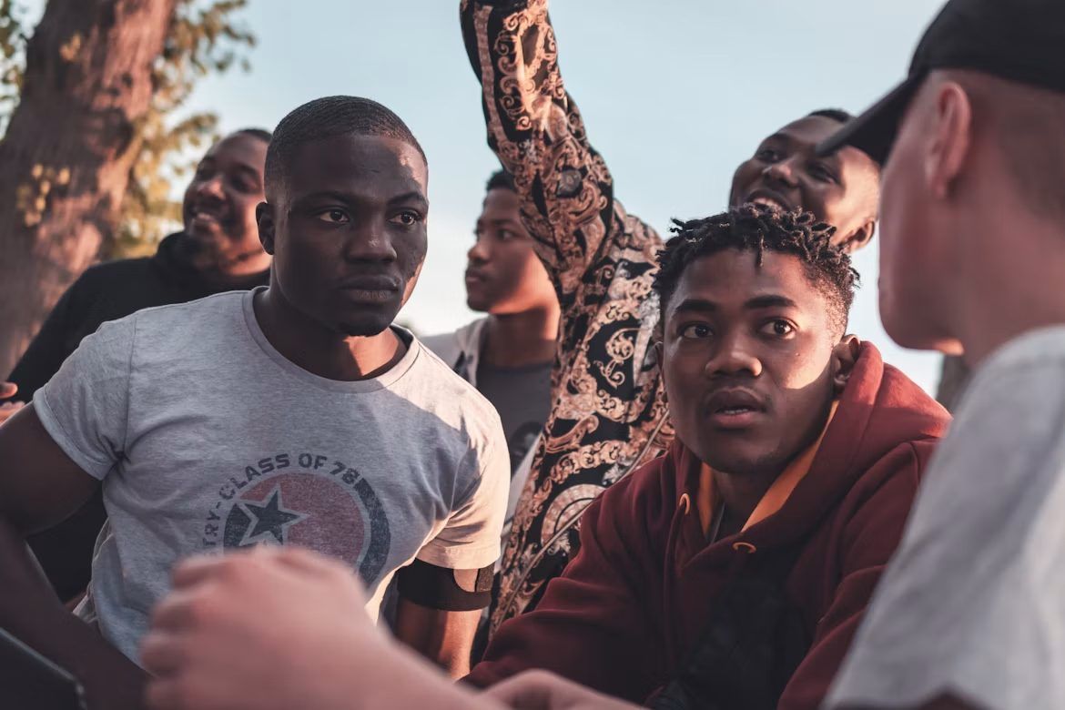 A group of young men talking together outdoors at sunset